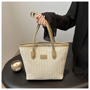 Close-up of beige woven tote bag showing detailed V-shaped texture and leather handle