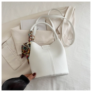 Detail der weißen Eimer-Tasche aus Leder mit Fashion-Prägung und Seidenschal-Griff