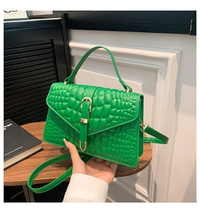 Detail of green crocodile texture handbag with gold buckle and adjustable strap