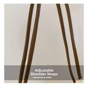 Detailed macro view of adjustable brown leather straps with fine stitching on tote bag