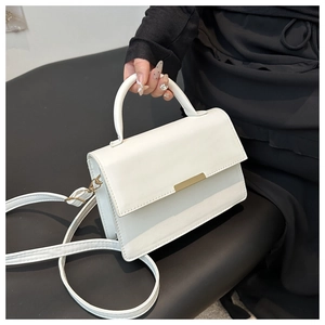 Detailed view of white minimalist handbag with curved handle and golden metal buckle