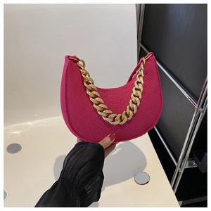Detail van rozerode vilten tas met krokodillenstructuur en grove gouden ketting