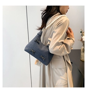Blue denim tote bag with chic bow accents and elegant pearl shoulder strap detail