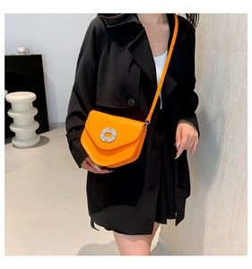 Sacoche orange à boucle en strass portée sur un blazer noir pour un look sophistiqué