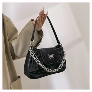 Détail du sac bandoulière en cuir verni noir avec papillon argenté et décor de chaîne