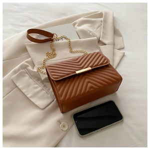 Close-up of caramel V-quilted faux leather crossbody bag with elegant gold chain strap
