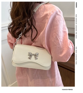 Detail of cream white PU leather crossbody bag with silver butterfly bow and chain
