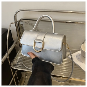 Vista macro di una borsa a mano argento metallizzato con una fibbia dorata a forma di U dorata