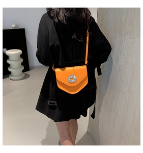 Détail d'un sac bandoulière orange vif avec une boucle scintillante ornée de strass cristal