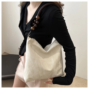 Detail of beaded shoulder strap on cream hobo bag with pleated texture finish