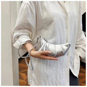 Detail of silver croissant bag featuring metallic texture and smooth zipper closure