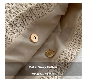 Detail of the magnetic snap closure and internal lining on a woven straw tote bag