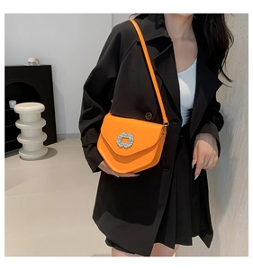 Détail d'un sac à bandoulière orange vif avec boucle en strass et rabat en forme d'enveloppe