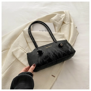 Détail d'un sac sous les aisselles en cuir texturé noir sur une veste en tweed blanc