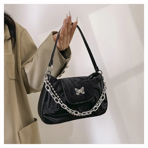Détail du sac à bandoulière noir brillant avec boucle papillon et chaîne en métal argenté
