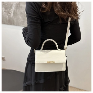 Detailed view of a white minimalist crossbody bag with gold metal buckle on a model