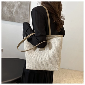 Detail of hand-woven straw tote bag with premium faux leather handles and textured finish