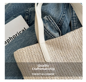 Detail of herringbone weave texture and white leather handle on beige straw tote bag