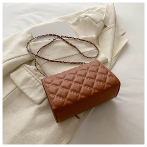 Detail of caramel brown quilted leather shoulder bag with classic woven chain strap