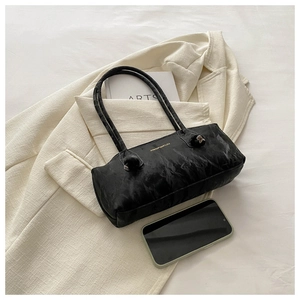 Gros plan d'un sac à bandoulière en cuir noir marbré avec logo doré sur un blazer crème