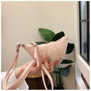 Close-up of soft pink mini croissant bag with pleat details and slim leather handle