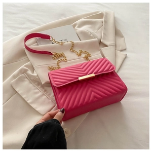 Detailed close-up of hot pink chevron quilted shoulder bag with gold chain strap on blazer