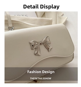 Close-up of white crossbody bag featuring a silver metal butterfly buckle on smooth leather