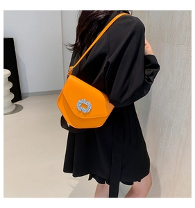Détail du sac orange vif avec boucle en strass de luxe et bandoulière élégante