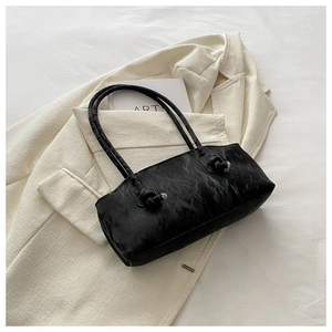Détail du sac à bandoulière noir avec texture marbrée et poignée à nœuds décoratifs