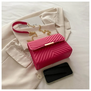 Close-up of hot pink chevron quilted bag with gold metal clasp and chain strap detail