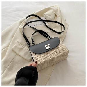 Detail of woven straw shoulder bag with black leather flap and silver metal twist lock