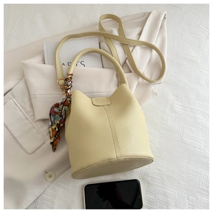 Detail der beigen Beuteltasche mit Litschi-Struktur und Seidentuch auf einem Anzug