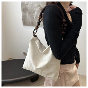 Detail of retro beige tote bag with unique dark brown wooden bead shoulder strap