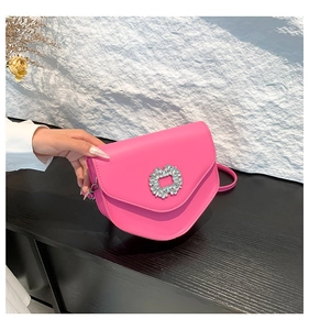 Détail du sac selle rose fuchsia avec boucle en cristal brillant sur cuir texturé
