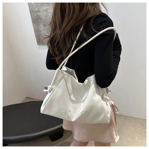 Dettaglio borsa hobo bianca in pelle con lettere a rilievo e tracolla con nodo decorativo