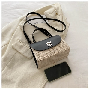 Close-up of woven straw bag showing black leather flap and silver metal twist lock detail