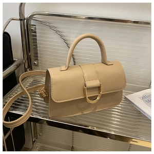 Dettaglio borsa a mano beige in pelle con fibbia a D dorata e tracolla regolabile
