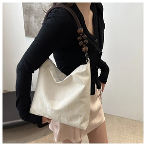 Close-up of velvet shoulder bag with unique wrinkled texture and wooden bead strap detail