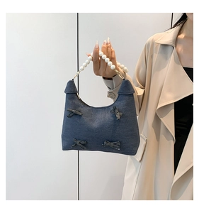 Detail of denim tote bag with four bows and white faux pearl beaded handle strap