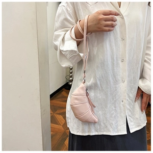 Detail view of a pink croissant-shaped mini bag with fine stitching and a slim strap