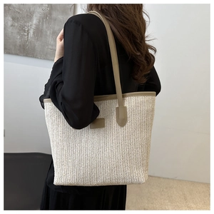 Macro shot of minimalist woven tote bag with beige herringbone texture and leather straps