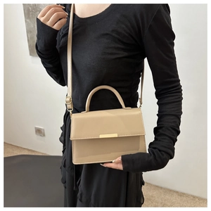 Detailed view of beige crossbody bag with gold buckle and adjustable shoulder strap