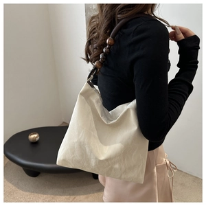 Detail of beaded shoulder strap on a cream hobo bag with natural crinkle texture