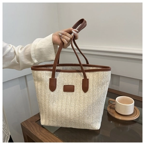 Detailed view of large straw tote bag with woven texture and brown faux leather trim