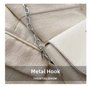 Detailed macro view of high-quality silver metal hardware hooks and chain on white bag