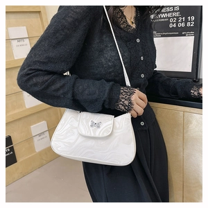 Détail du sac à bandoulière blanc à motif marbré avec logo papillon porté par un modèle