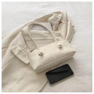 Gros plan du sac porté épaule crème avec texture marbrée et détail de nœud élégant