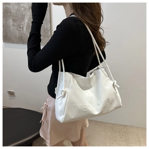 Dettaglio borsa tote bianca in morbida pelle con nodi decorativi e logo in rilievo