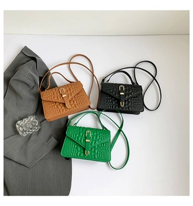 Detailed view of crocodile pattern small square bags in brown black and green colors
