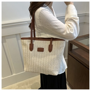 Detailed view of large woven tote bag with brown leather handles worn by a model